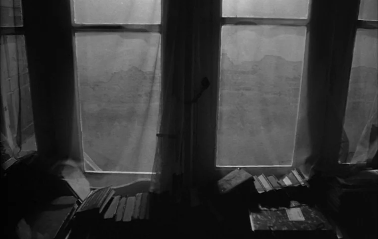 Werckmeister Harmonies (2000) movie still: establishing — A cluttered interior office features multiple windows overlooking a distant landscape…