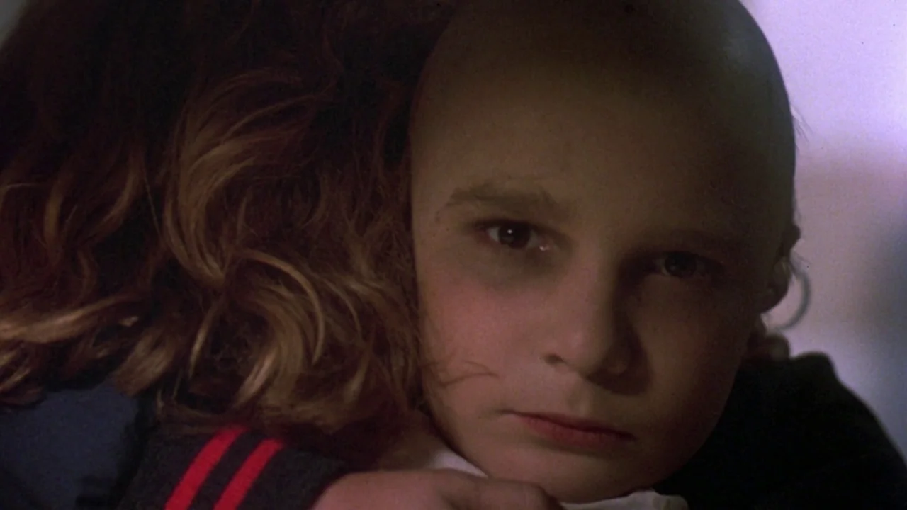 Friday the 13th: The Final Chapter (1984) movie still: closeup — A close-up captures two children embracing in a dim, shadowed indoor space. One…