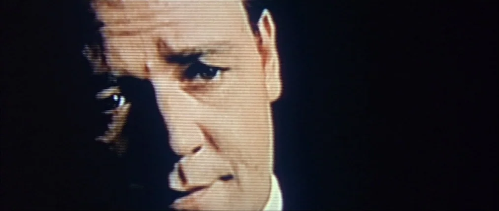 The Insider (1999) movie still: closeup — A man's face is illuminated from the side against a dark, featureless void. The image exhibits visible…