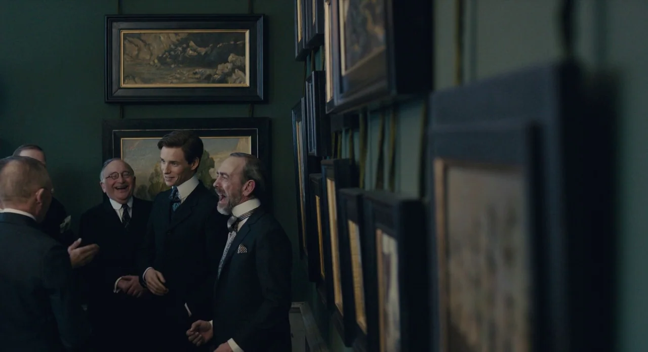 The Danish Girl (2015) movie still: medium — A dark green walled space features numerous framed oil paintings hung in close proximity. A group of…