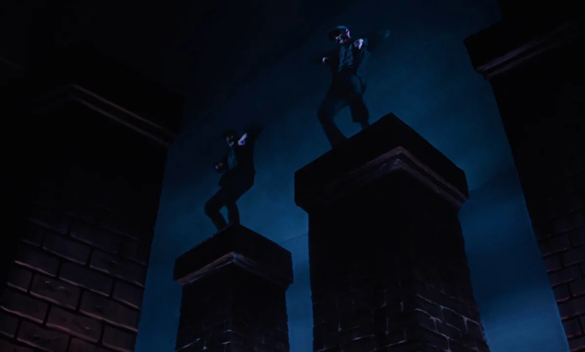 Mary Poppins (1964) movie still: wide — Two men stand on top of tall, square brick chimneys at night. The figures are silhouettes against a dark…