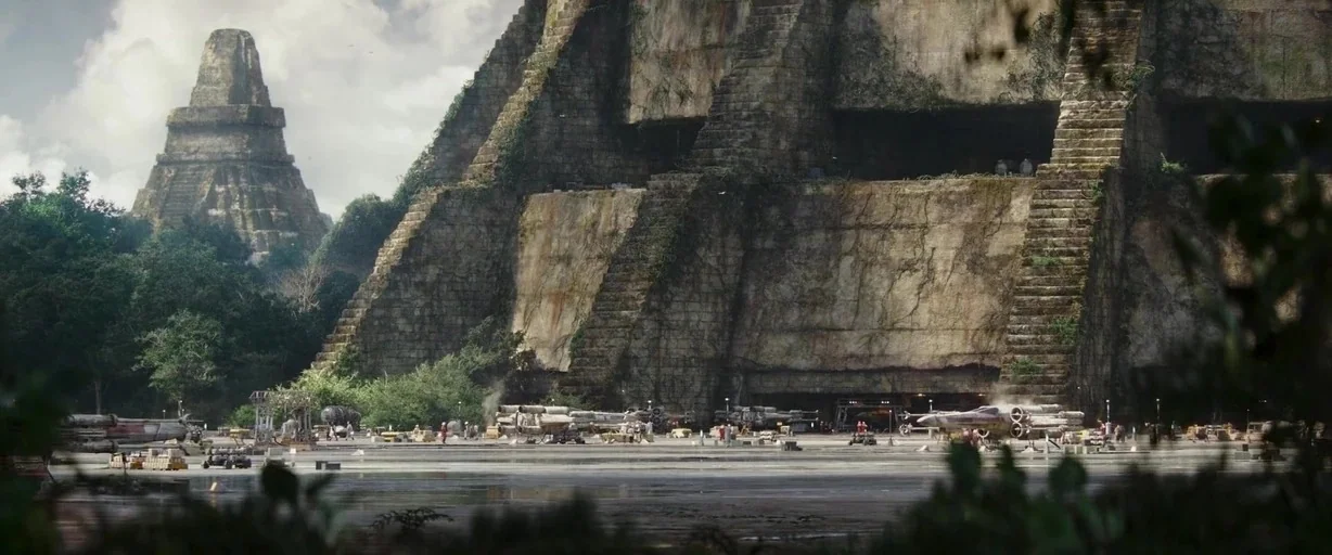 Rogue One: A Star Wars Story (2016) movie still: establishing — A massive, weathered stone ziggurat sits amidst dense, verdant jungle foliage in a…