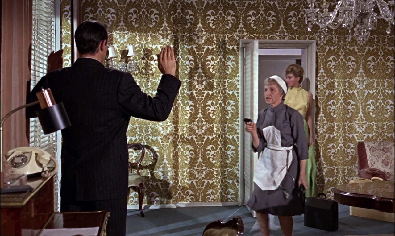 From Russia With Love (1963) movie still: fullbody — A hotel suite features intricate gold-patterned wallpaper and an open door to another room. A…