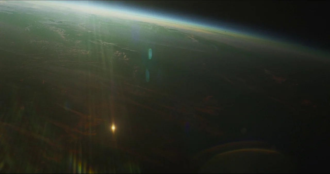 Prospect (2018) movie still: establishing — The curved horizon of the Earth is visible from space against the dark void. A thin glowing blue line…