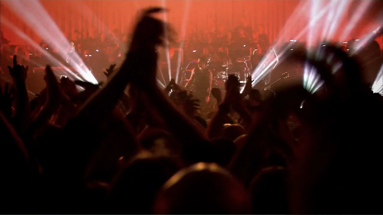 Soaring Highs and Brutal Lows: The Voices of Women in Metal (2015) movie still: wide — A crowded music concert venue features a performer on stage…