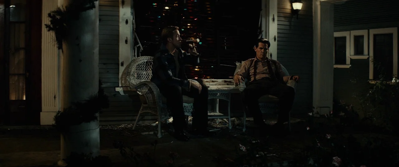 Gangster Squad (2013) movie still: wide — A dark, wood-paneled porch of a vintage home at night with decorative holiday lights. Two men sit in white…
