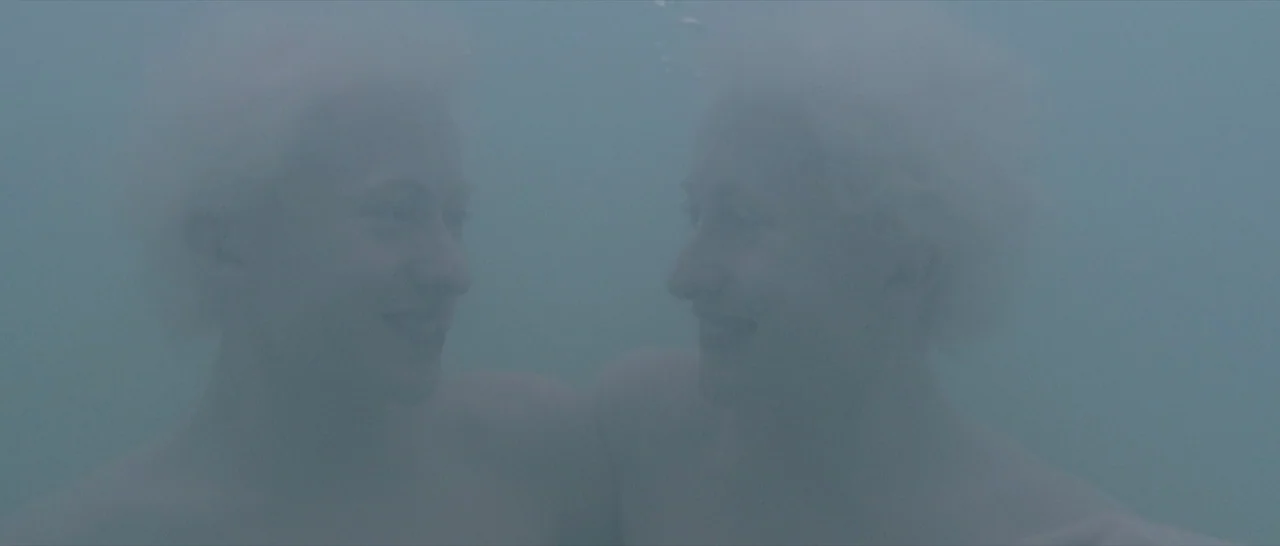 Tale of Tales (2015) movie still: medium — Two individuals are positioned underwater in a body of murky, light blue-green water. Their faces are…
