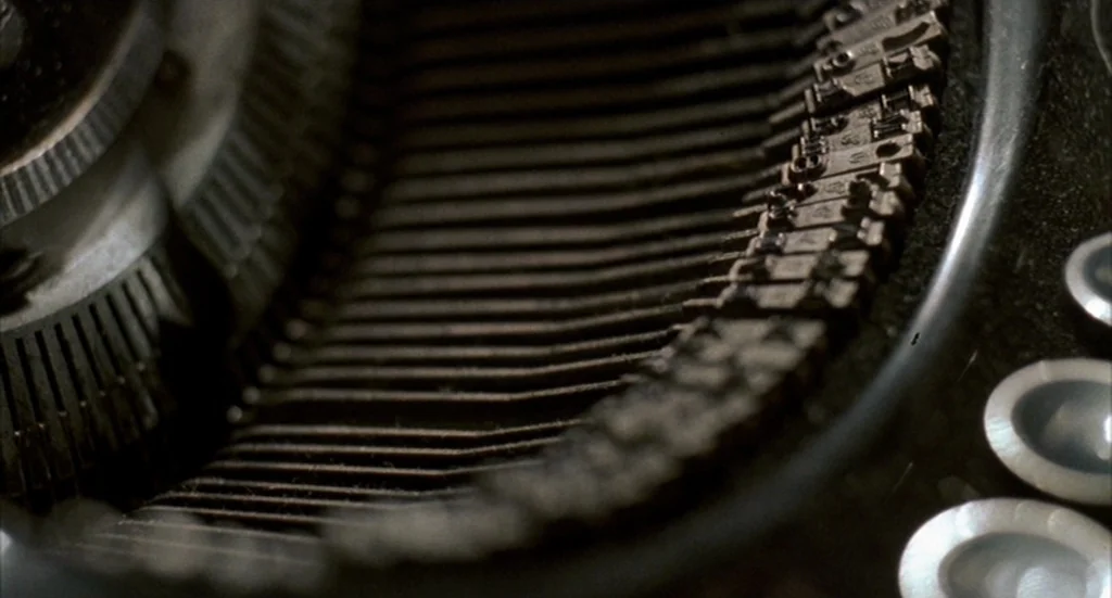 Barton Fink (1991) movie still: closeup — A close-up view shows the interior mechanisms of an old mechanical typewriter. The metal typebars are…