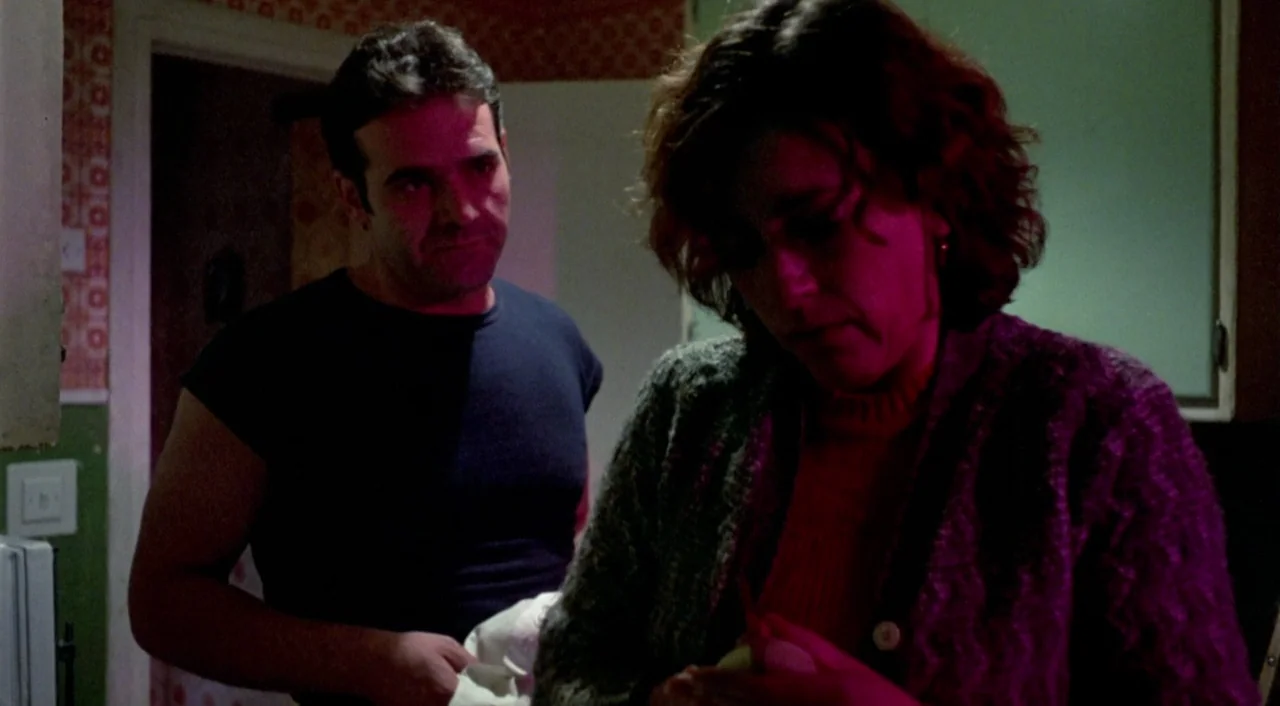 What Have I Done To Deserve This? (1984) movie still: medium — An interior kitchen space features dated patterned wallpaper and dark, shadowy…