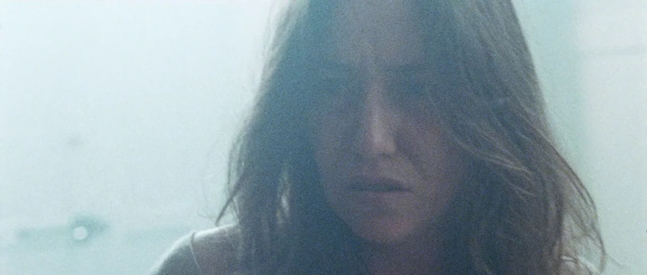 Alléluia (2014) movie still: closeup — A woman stands in a bright, diffuse interior space with high-key lighting. Her face is centered in the frame,…