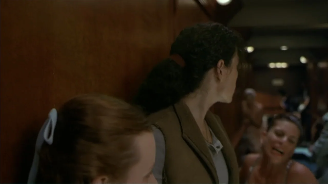 Ghost Ship (2002) movie still: medium — A narrow interior corridor features dark wood paneling on the walls. Two women stand in the foreground while…
