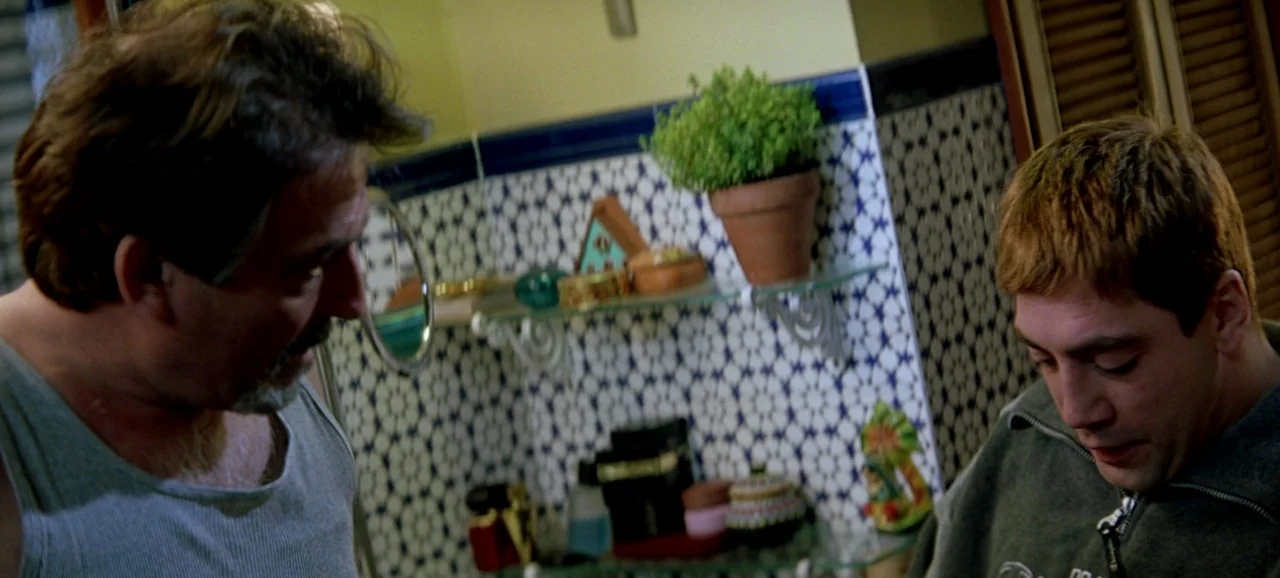 Live Flesh (1997) movie still: medium — A bathroom features walls decorated with blue and white geometric patterned tiles. Two men stand close…