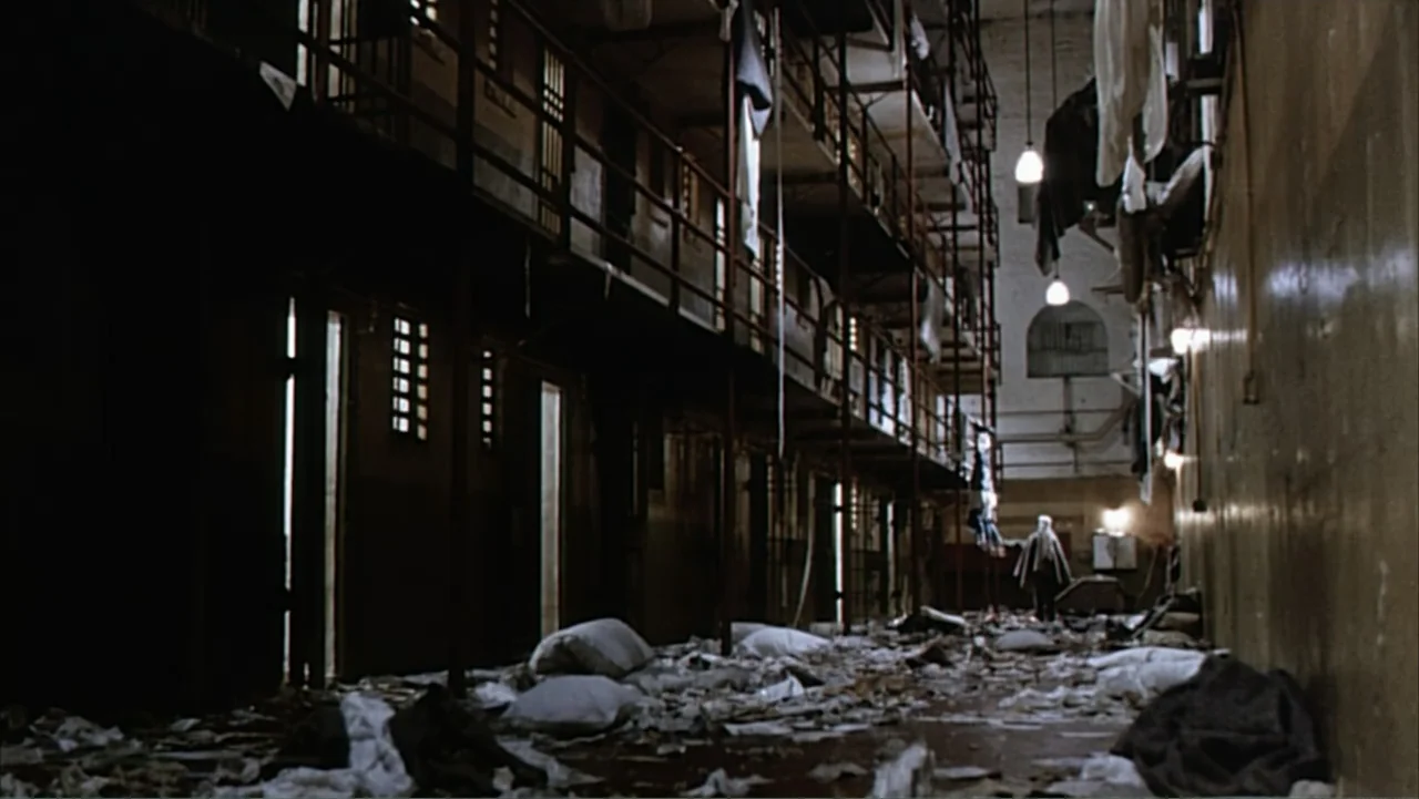 Against the Wall (1994) movie still: wide — A dilapidated multi-tiered prison block filled with scattered debris and laundry hanging from railings.…