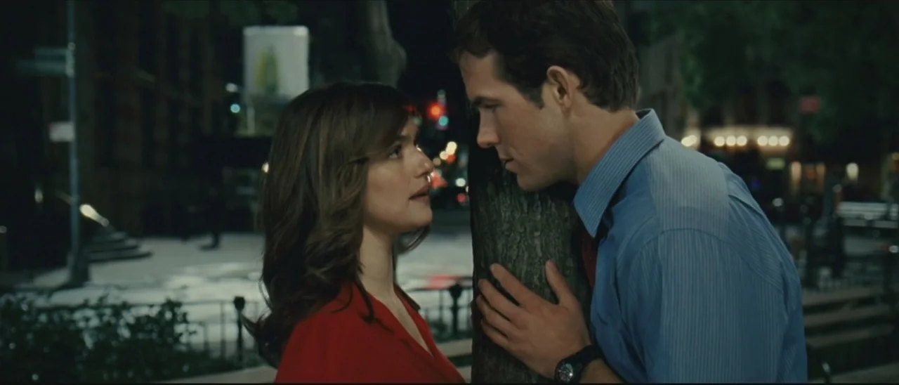 Definitely, Maybe (2008) movie still: medium — A night scene in a city park with a tree separating two people. A woman in a red top and a man in a…