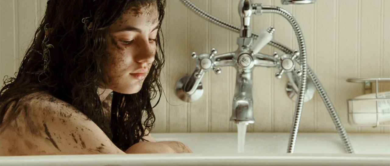 The New Daughter (2009) movie still: medium — A clean tiled bathroom features a vintage-style chrome faucet fixture over a white bathtub. A young…