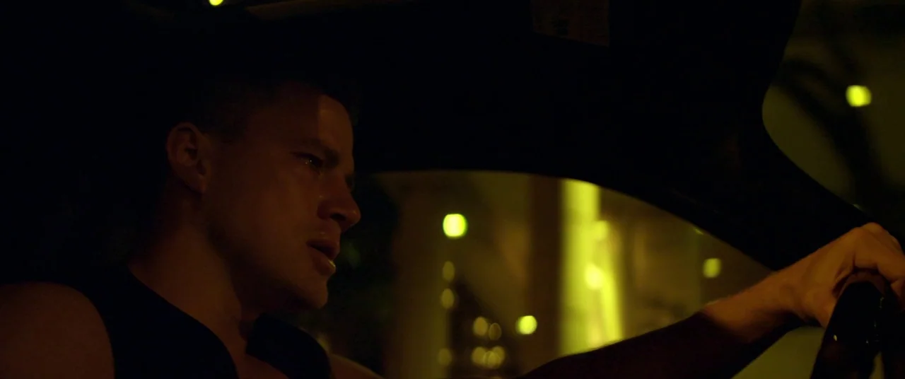 Magic Mike (2012) movie still: medium — A dark vehicle interior with the driver visible in profile against a night background. The driver holds the…