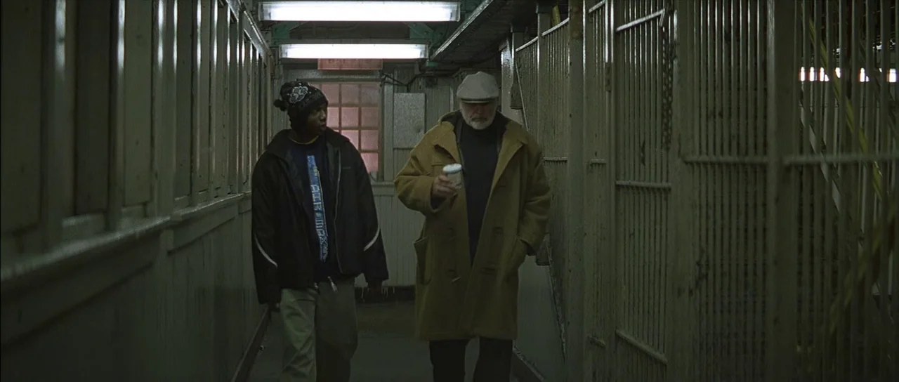 Finding Forrester (2000) movie still: fullbody — A narrow, institutional walkway features metal fencing and industrial overhead fluorescent light…
