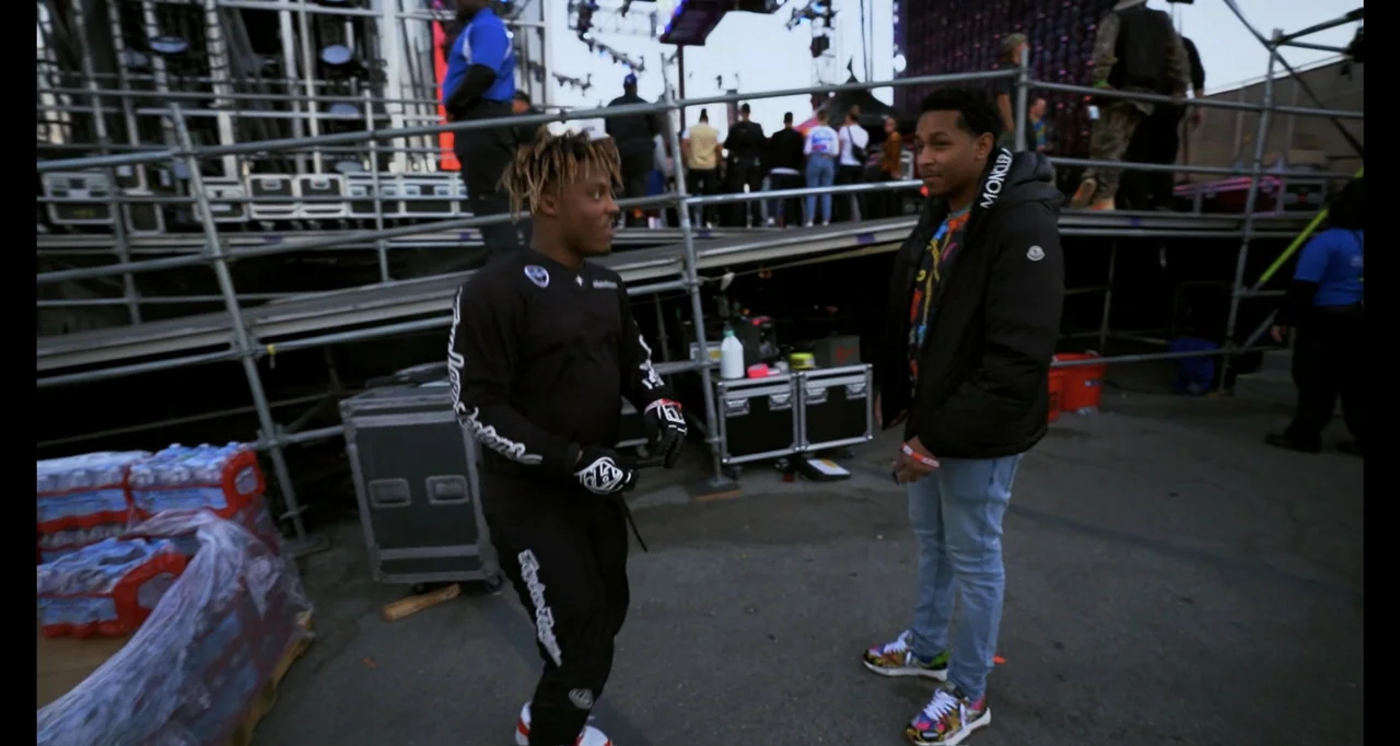 Juice WRLD: Into the Abyss (2021) movie still: fullbody — A festival backstage area features metal scaffolding, equipment cases, and crates of water…