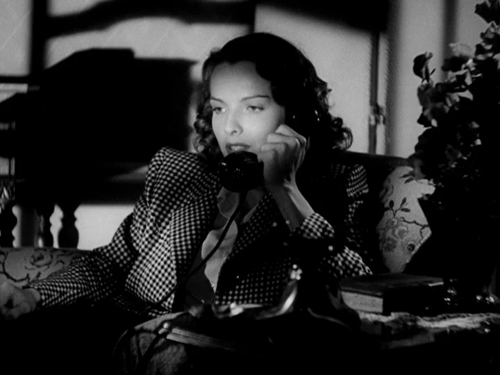 Stranger on the Third Floor (1940) movie still: medium — A dark 1940s room features a woman sitting on patterned furniture. She holds a black rotary…