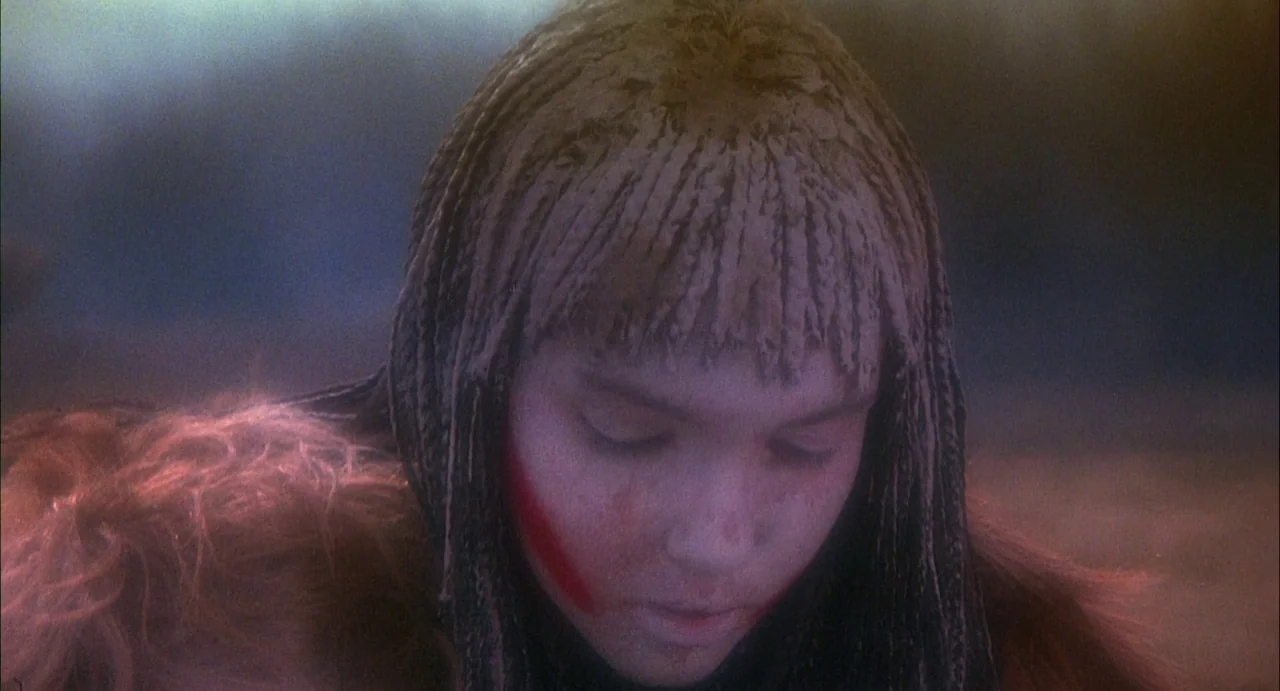 Conquest (1983) movie still: closeup — A field illuminated by soft, hazy light during the late afternoon. A teenage girl with braided hair and face…