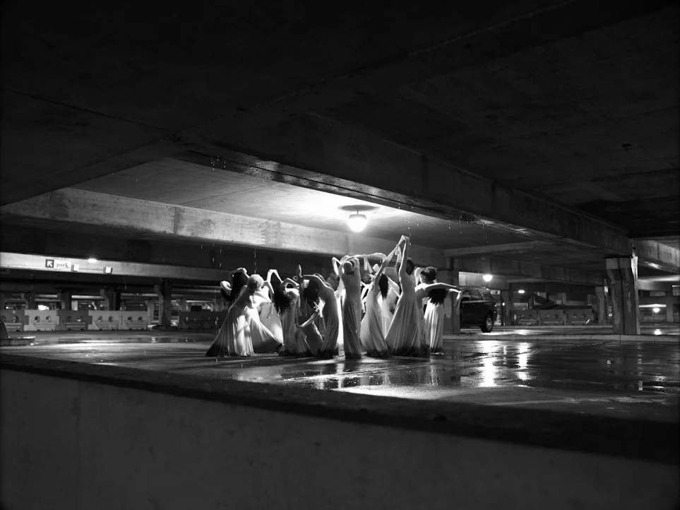 Lemonade (2016) movie still: wide — A concrete parking structure features a group of dancers huddled under a single light. The figures in flowing…