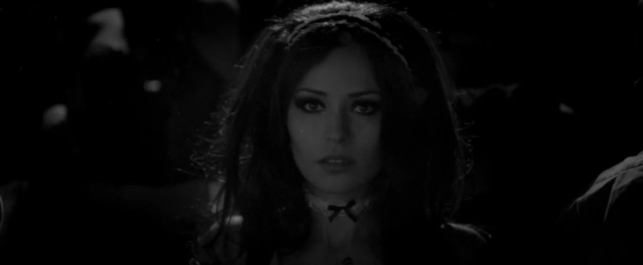 A Girl Walks Home Alone at Night (2014) movie still: closeup — A dark environment with indistinct shapes suggesting a crowded space or busy room. A…