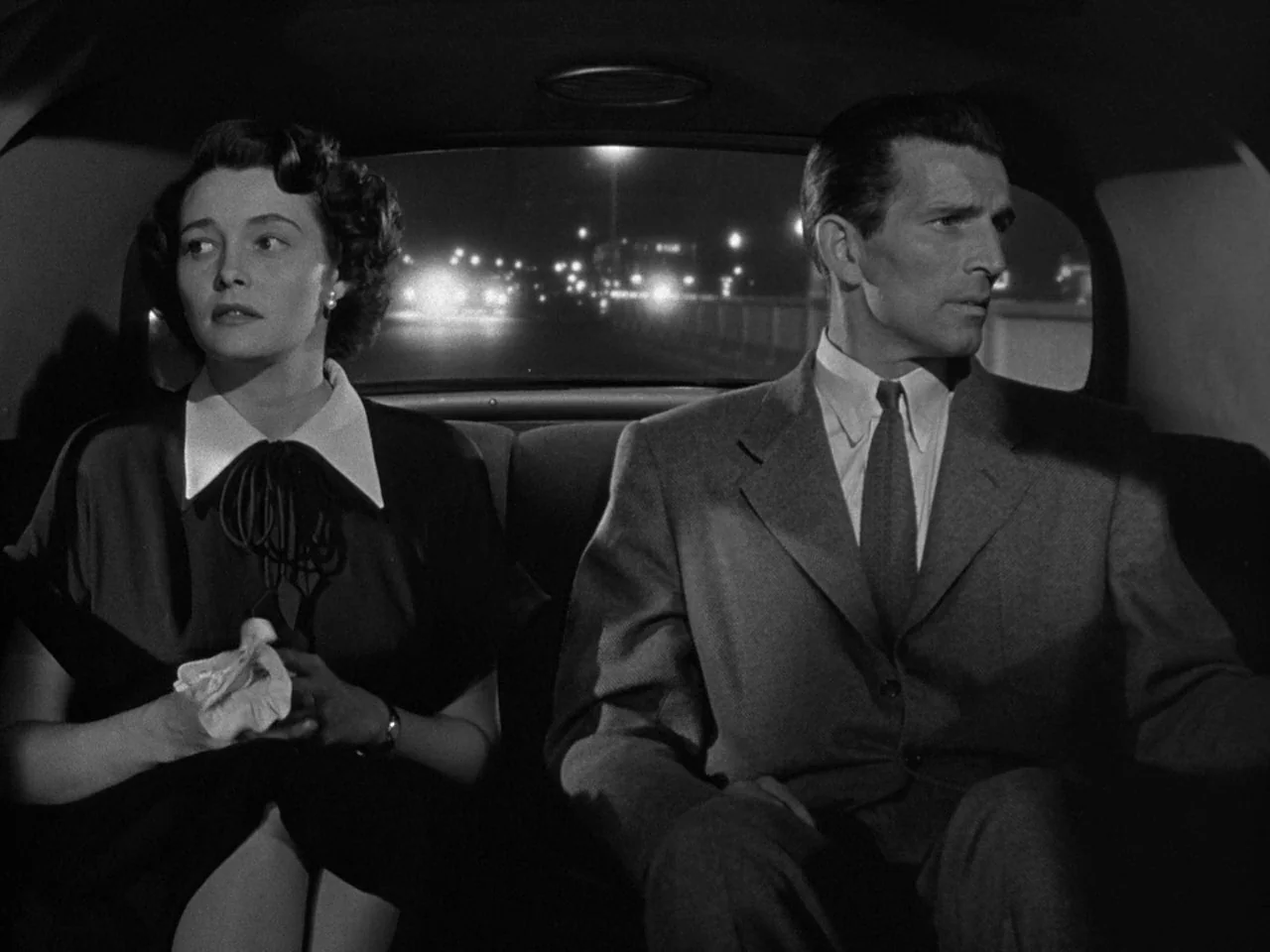 The Day the Earth Stood Still (1951) movie still: medium — A man and a woman sit in the backseat of a moving car at night. The city street lights…