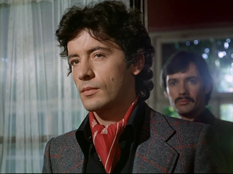 Fox and His Friends (1975) movie still: medium — An interior space features white curtains hanging in front of a window. Two men stand in the room…