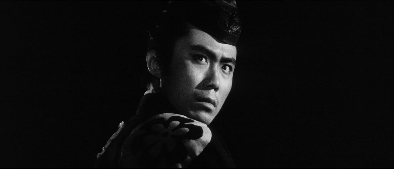 Kuroneko (1968) movie still: closeup — A man stands in total darkness with only his upper body and face lit. He turns his head and eyes to look…