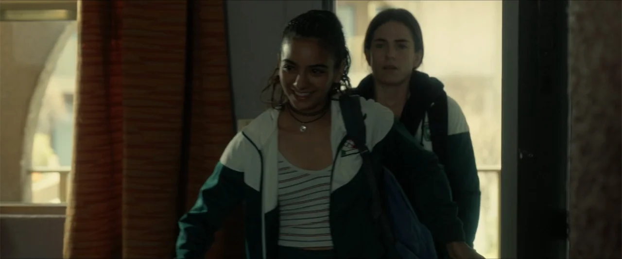 Dive (2013) movie still: medium — Two teenage girls enter a bright dormitory room during the daylight hours. They both wear track jackets and carry…