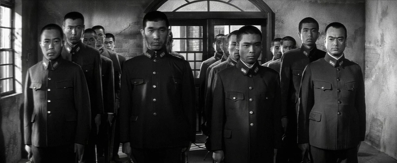 Story of a Prostitute (1965) movie still: medium — A group of Japanese soldiers stands at attention in a dimly lit, austere room. The men are…