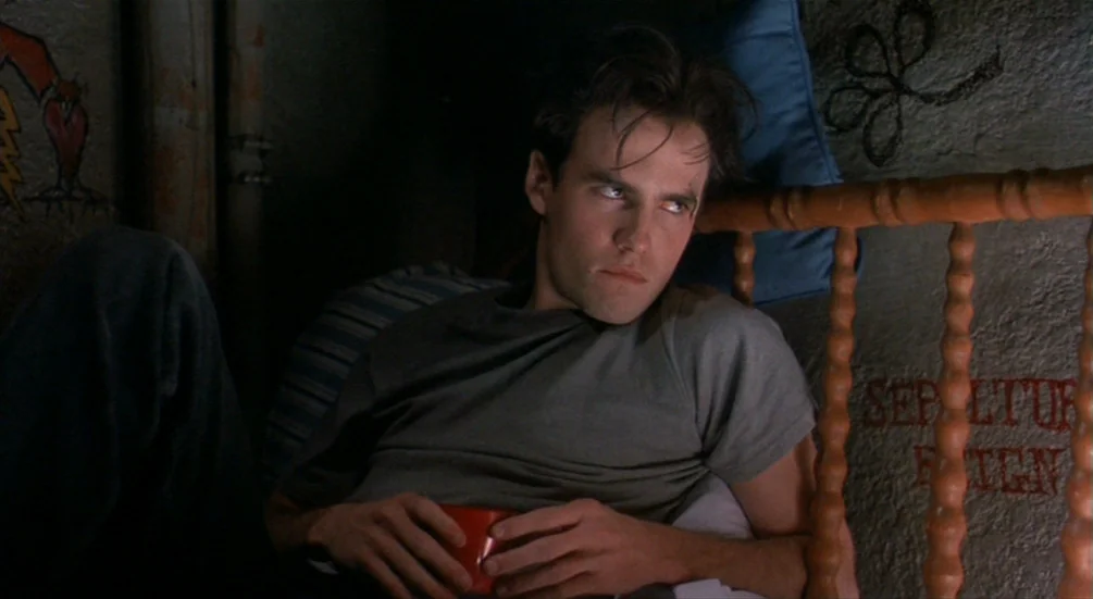 Freddy’s Dead: The Final Nightmare (1991) movie still: medium — A dimly lit room with textured, graffiti-marked concrete walls and a wooden…