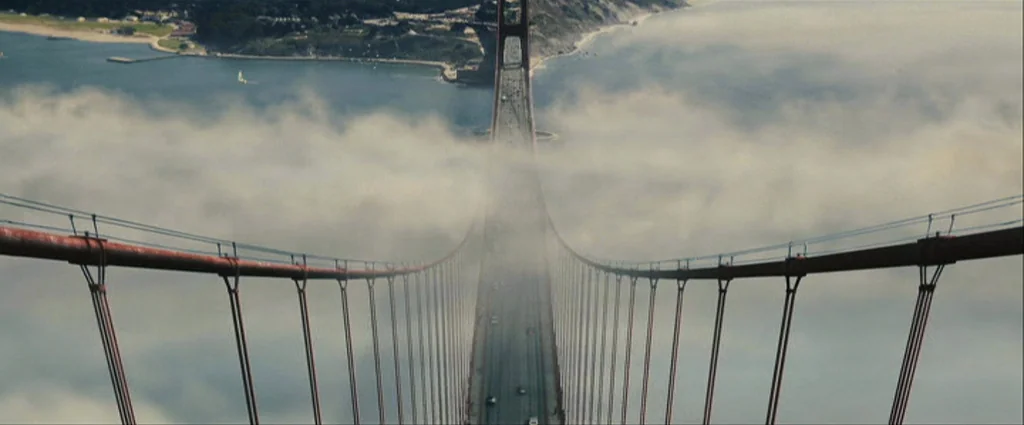 Zodiac (2007) movie still: establishing — A high-angle view looks directly down onto the red suspension cables of a bridge. Thick white fog obscures…
