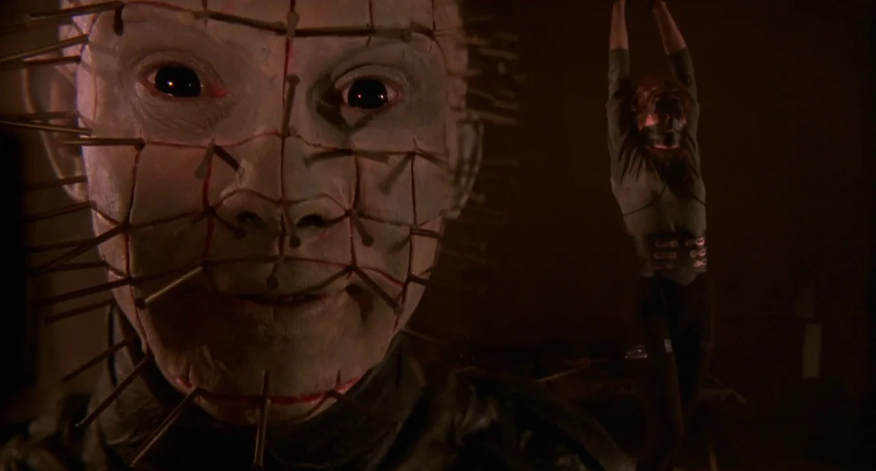 Hellraiser III: Hell on Earth movie still: closeup — A dark, nondescript chamber contains a figure with a pin-covered head in the foreground. A…