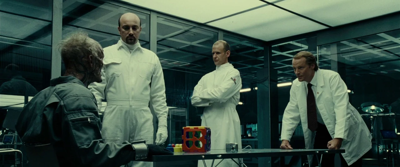 Resident Evil: Extinction (2007) movie still: medium — A sterile, modern laboratory with glass partitions and overhead fluorescent panels. Three men…