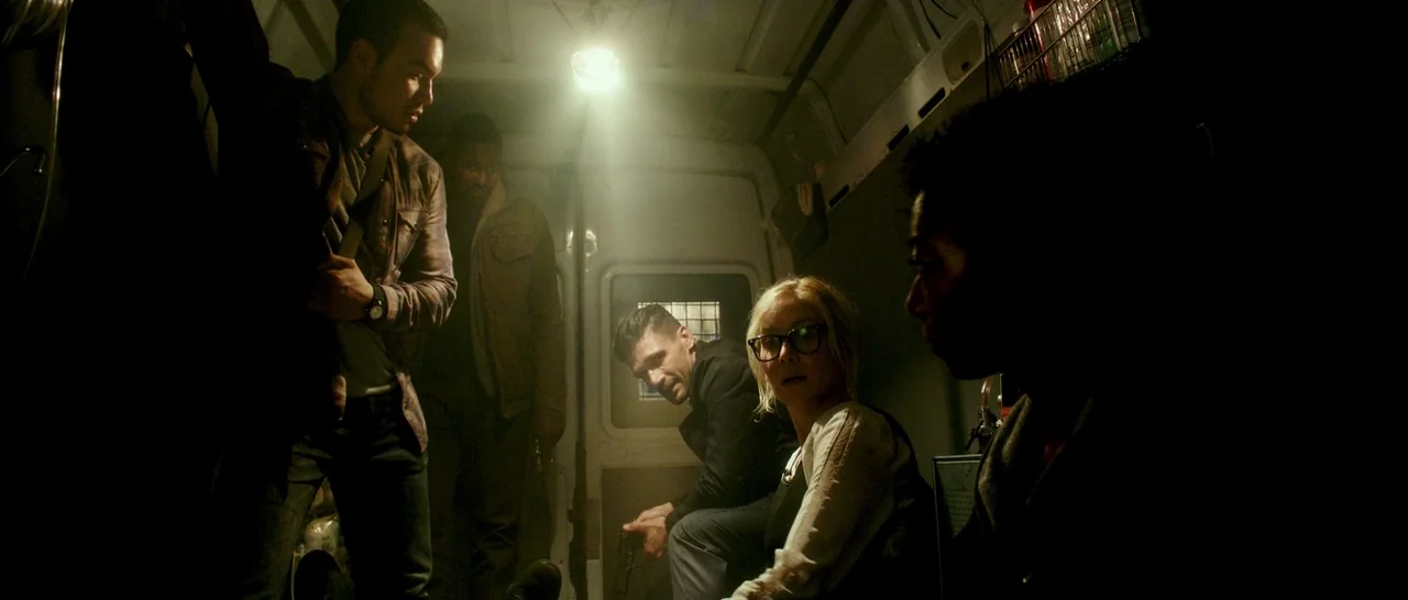 The Purge: Election Year (2016) movie still: medium — A cramped, dimly lit cargo area inside a van with metallic interior walls. A small group of…