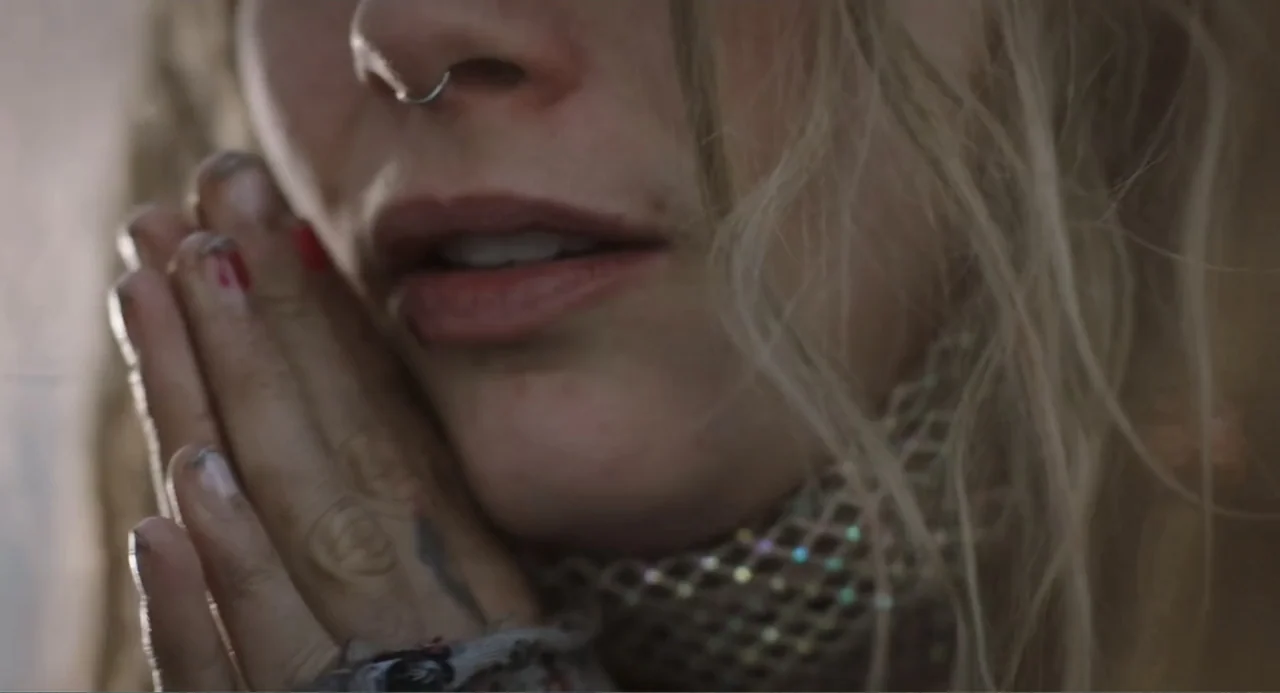 Elles (2018) movie still: closeup — A close-up shot focuses on a person's face and joined hands. The subject presses her hands together with long…
