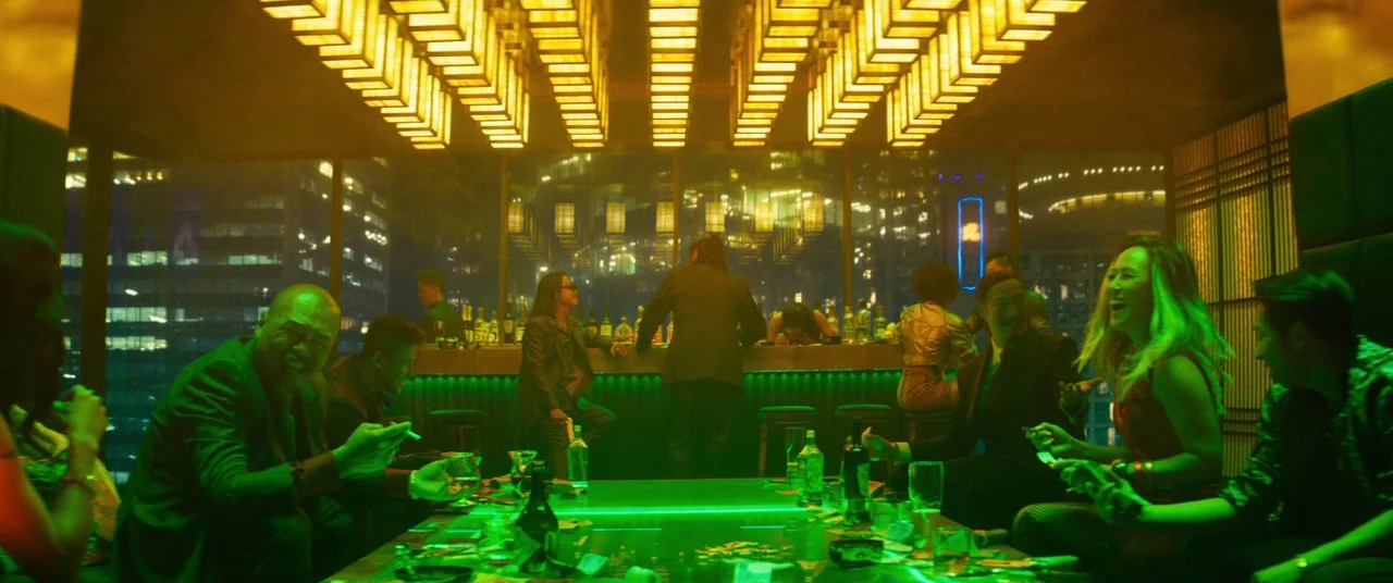Deadpool 2 (2018) movie still: wide — A luxury high-rise lounge overlooks a dark city with a glowing green central table. A group of diverse people…