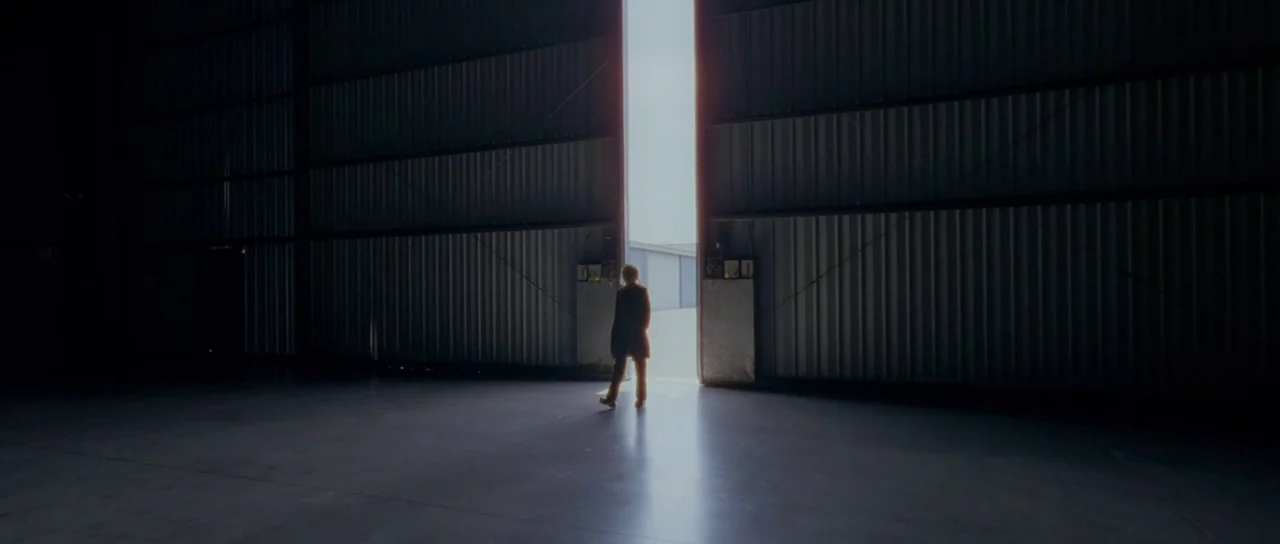 Knight of Cups (2015) movie still: wide — A vast, dark industrial space with corrugated metal walls and concrete floor. A single person stands…