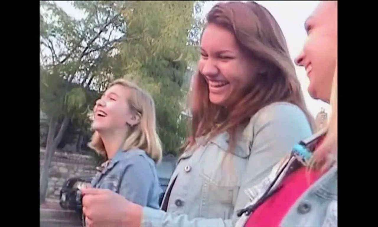 Ham on Rye (2019) movie still: medium — Three teenage girls laugh while walking along a suburban street lined with trees. A dark car is parked near…