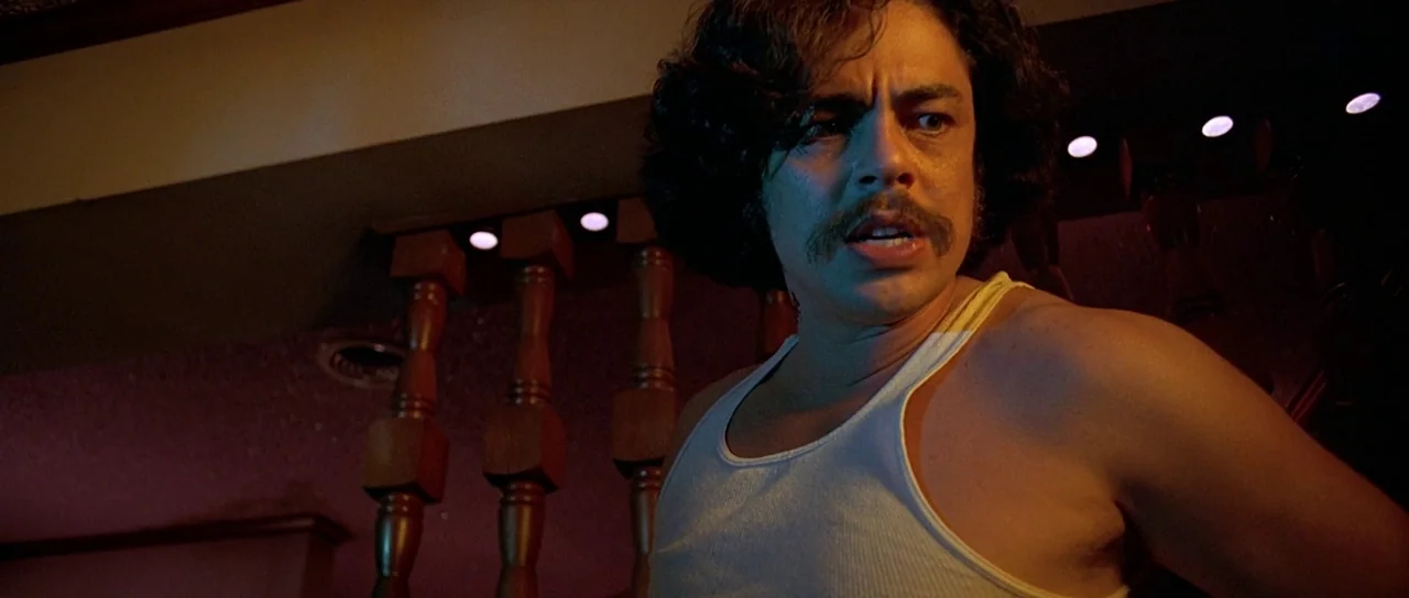 Fear and Loathing In Las Vegas (1998) movie still: medium — A man stands near wooden balusters inside a darkened room with ambient accent lighting.…
