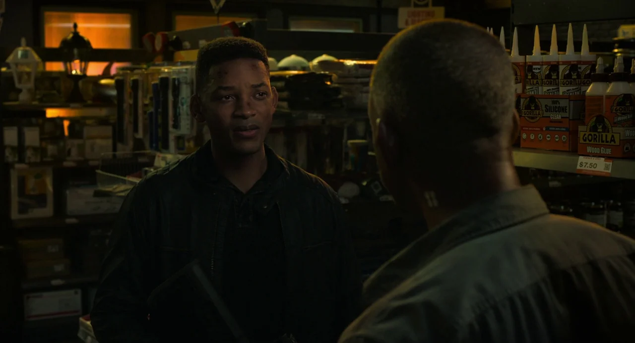 Gemini Man (2019) movie still: medium — An aisle in a retail store filled with various hardware and adhesive products. Two men stand facing each…