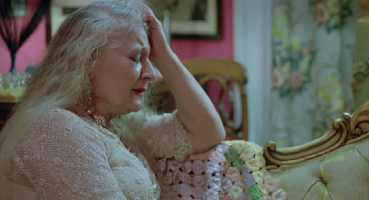 Ms. 45 (1981) movie still: medium — An interior space features floral wallpaper and ornate vintage furniture. An older woman with white hair sits…