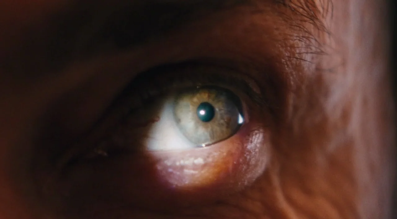 Phantom Thread (2017) movie still: closeup — An extreme close-up focuses on a human eye with distinct green and gold coloring. The surrounding skin…