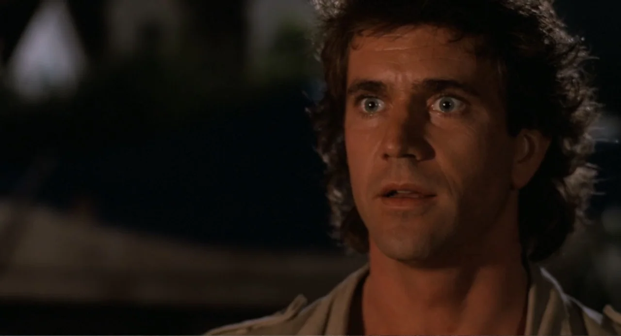 Lethal Weapon (1987) movie still: closeup — A man stands outdoors at night with a dark, blurred background visible behind him. The man has wide eyes…