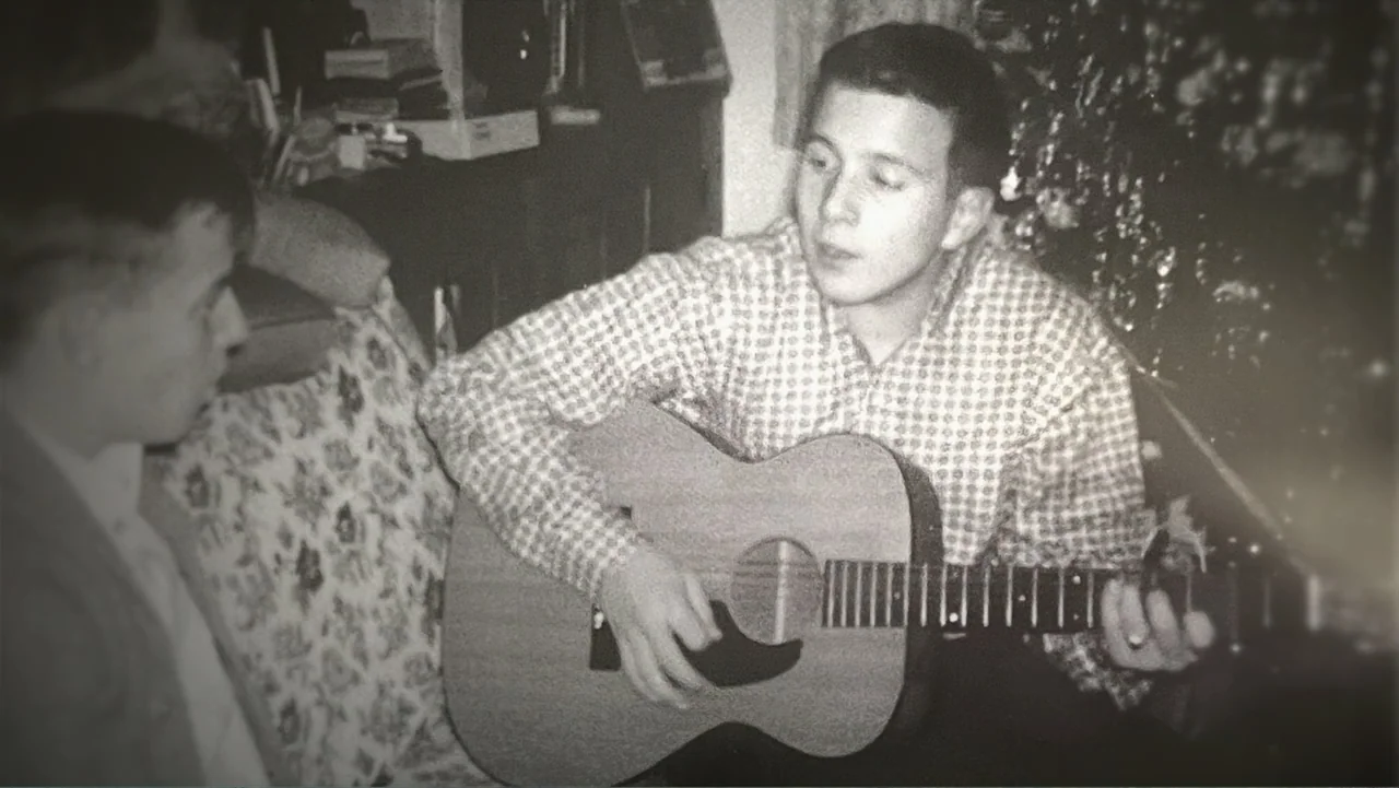 The Day the Music Died: The Story of Don McLean's "American Pie" (2022) movie still: medium — A dimly lit room with vintage furniture and a floral…