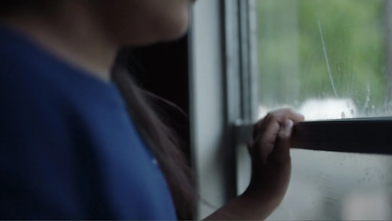 Torn Apart: Separated at the Border (2019) movie still: closeup — Inside a bus, a window with a smudged pane provides a view of blurred trees. A…