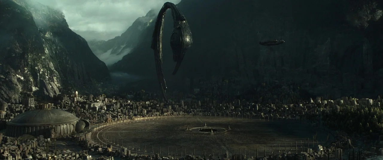 Alien: Covenant (2017) movie still: establishing — A vast futuristic metropolis is nestled deep within a steep, shadowed mountain valley. A large,…