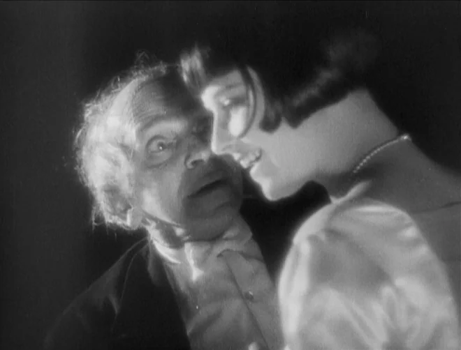 Pandora’s Box (1929) movie still: closeup — An interior space with high-contrast lighting typical of 1920s silent cinema expressionism. An older man…