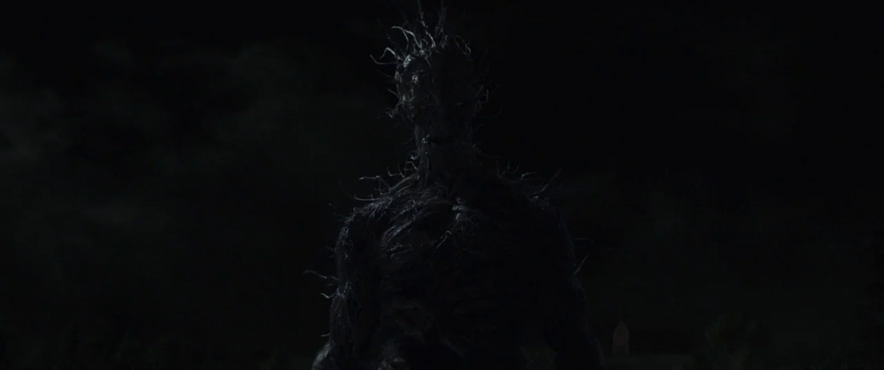 A Monster Calls (2016) movie still: medium — A dark night landscape features a looming figure made of twisted roots and branches. The massive…